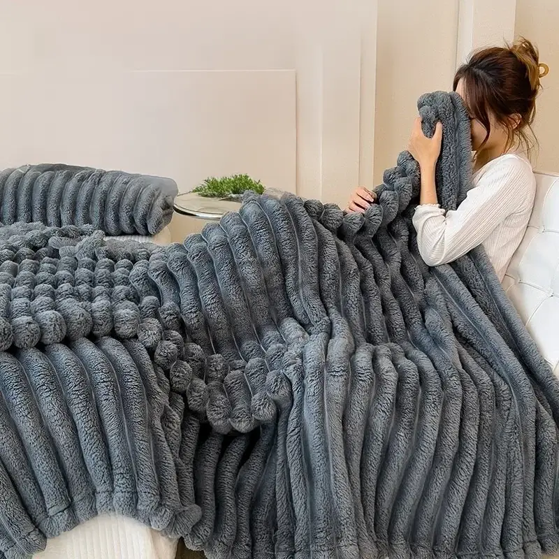 une avec assise sur son lit avec une couverture en flanelle à larges rayures épaisses